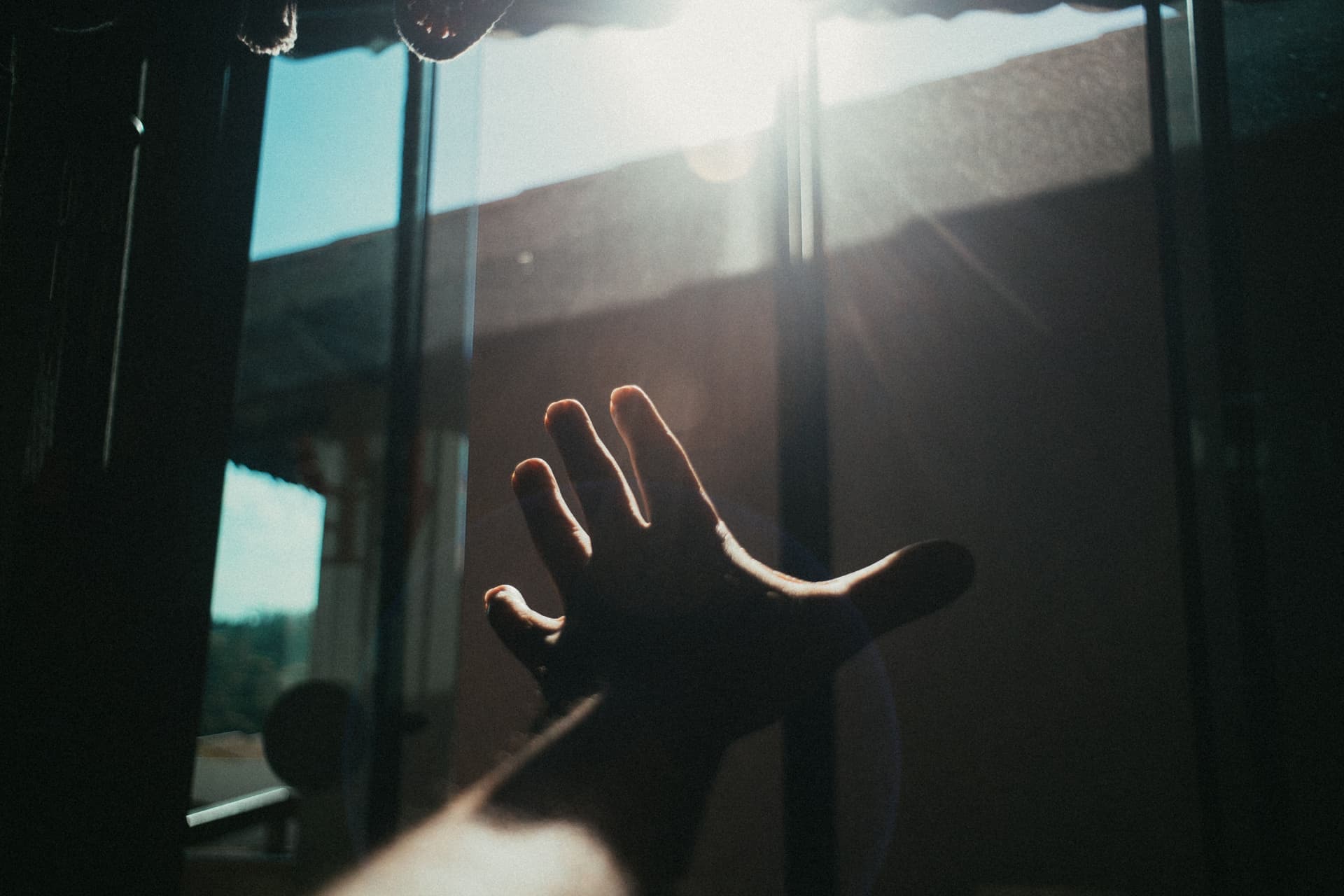 A hand reaching toward a device mounted high on a wall