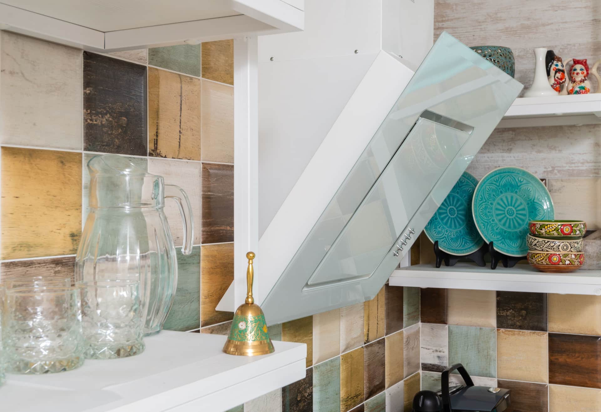 A fire blanket pouch mounted on a kitchen wall with the pull tab hanging free